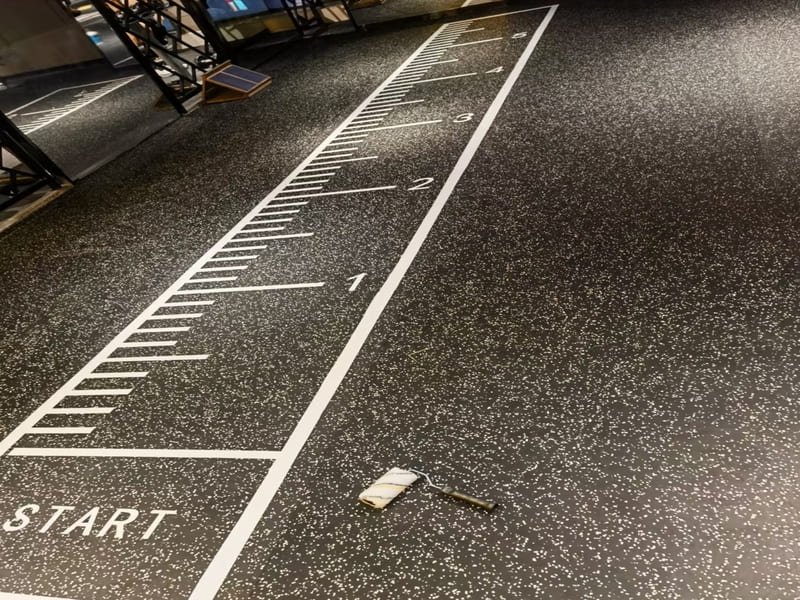 An engineer examining the cross-section of a custom rubber flooring sample with an inlaid logo.